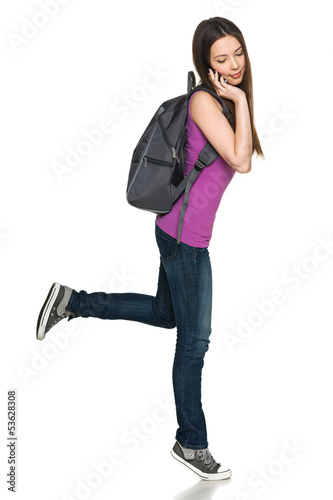 Photo: Full length of female with backpack talking on cell phone Full length of female with backpack talking on cell phone