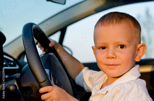 Photo: Little boy sitting behind the wheel of a car Little boy sitting behind the wheel of a car