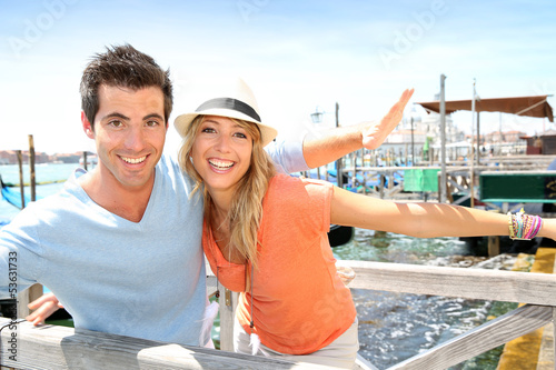 Photo: Cheerful couple stretching arms on a bridge in Venice Cheerful couple stretching arms on a bridge in Venice