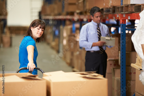 Photo: Female Worker Pulling Pallet In Warehouse Female Worker Pulling Pallet In Warehouse