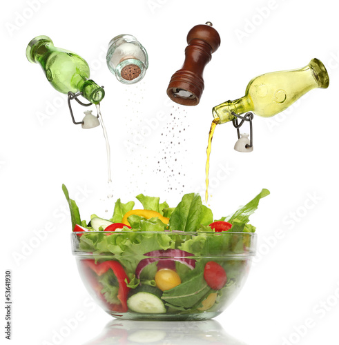 Photo: Pouring condiments on a colorful salad. isolated Pouring condiments on a colorful salad. isolated