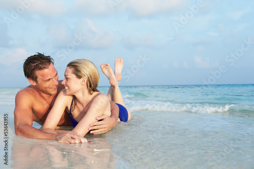 Photo: Romantic Couple Lying In Sea On Tropical Beach Holiday Romantic Couple Lying In Sea On Tropical Beach Holiday