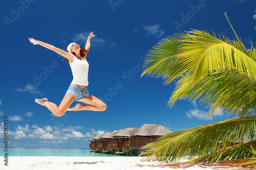 Photo: Happy young woman jumping on the beach Happy young woman jumping on the beach