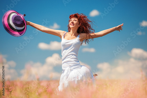 Photo: Cute woman running in the field with flowers Cute woman running in the field with flowers
