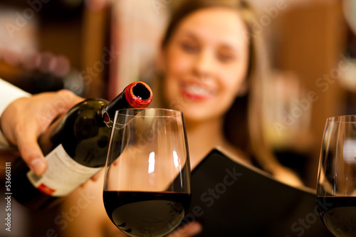 Photo: Waiter pouring red wine to a woman Waiter pouring red wine to a woman