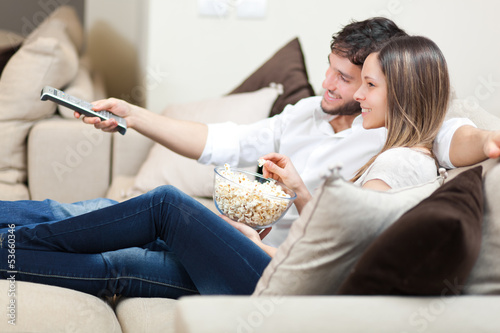 Photo: Happy young couple watching television together at home Happy young couple watching television together at home