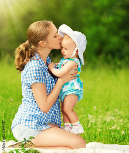 Photo: happy family on a walk. mother kissing baby happy family on a walk. mother kissing baby