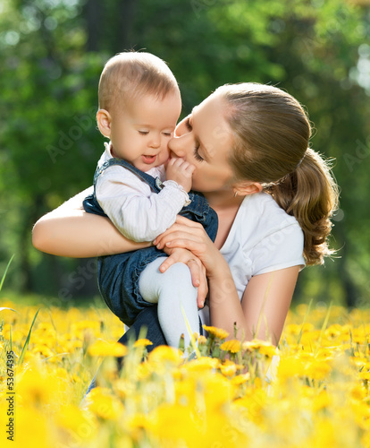 Photo: happy family on a walk. mother kissing baby happy family on a walk. mother kissing baby
