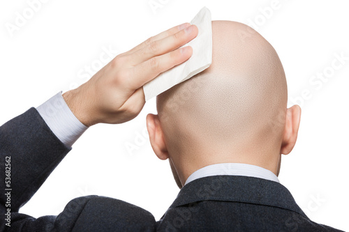 Photo: Hand holding tissue wiping or drying bald sweat head Hand holding tissue wiping or drying bald sweat head