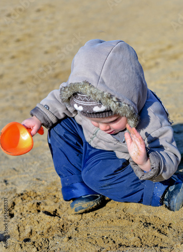 Photo: Cute child playing on the wet beach sand Cute child playing on the wet beach sand