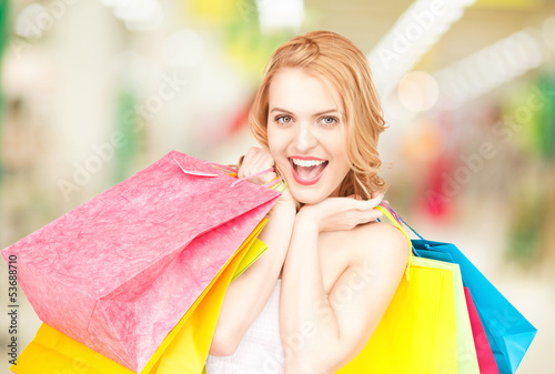 Photo: woman holding color shopping bags in mall woman holding color shopping bags in mall