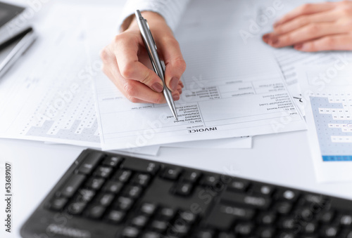 Photo: woman hand filling in invoice paper woman hand filling in invoice paper