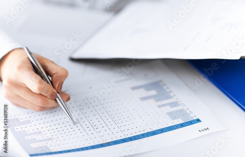 Photo: woman hand wrtiting on paper with numbers woman hand wrtiting on paper with numbers