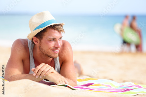 Photo: Man on beach lying in sand looking to side Man on beach lying in sand looking to side