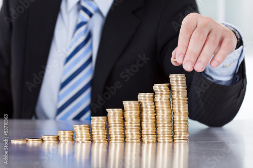 Photo: Close-up Of Businessman Hand Put Coins To Stack Of Coins Close-up Of Businessman Hand Put Coins To Stack Of Coins