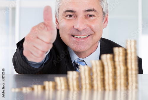 Photo: Businessman With Coins Showing Thumbs Up Sign Businessman With Coins Showing Thumbs Up Sign