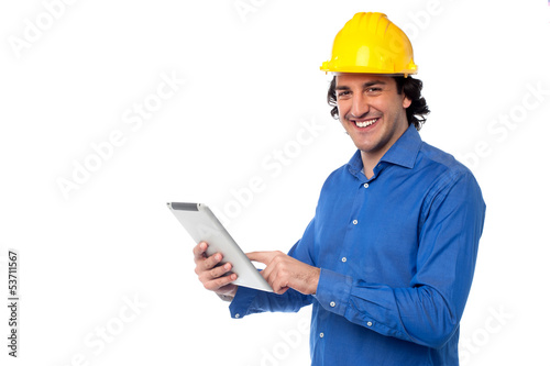 Photo: Construction worker operating tablet pc Construction worker operating tablet pc