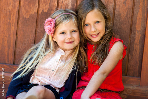 Photo: Two attractive girls next to wooden wall. Two attractive girls next to wooden wall.