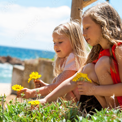 Photo: Two girls picking flowers. Two girls picking flowers.