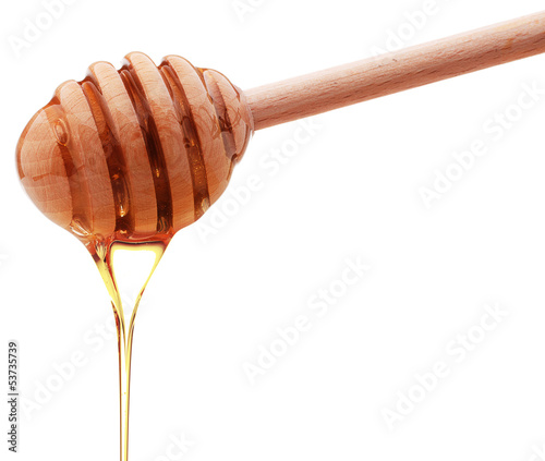 Photo: Honey dripping from a wooden honey dipper isolated on white back Honey dripping from a wooden honey dipper isolated on white back