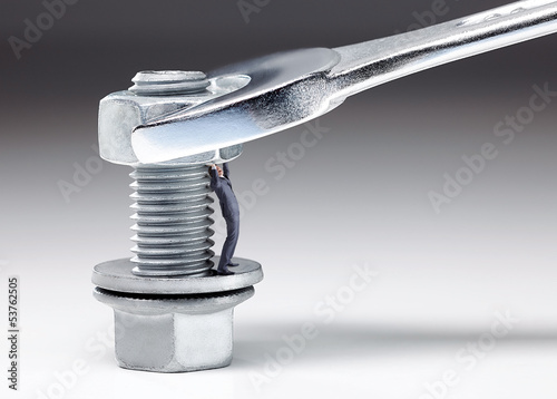 Photo: Business man between bolt and nut under pressure Business man between bolt and nut under pressure