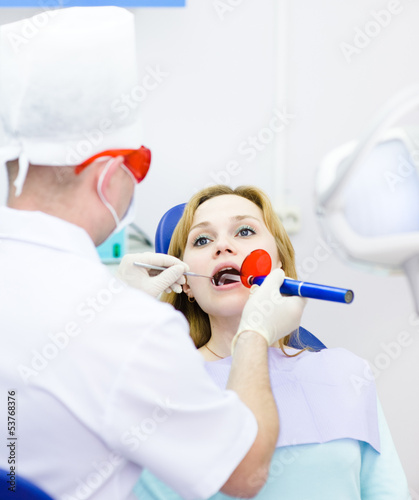 Photo: woman with open mouth receiving dental filling drying procedure. woman with open mouth receiving dental filling drying procedure.