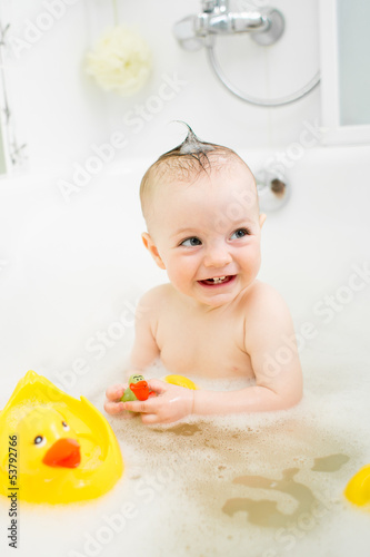 Photo: smiling baby girl taking bath and playing with toys smiling baby girl taking bath and playing with toys