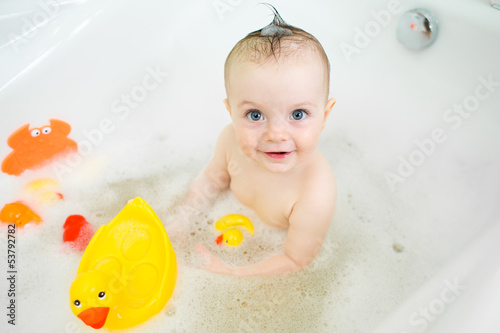 Photo: smiling baby girl taking bath and playing with toys smiling baby girl taking bath and playing with toys