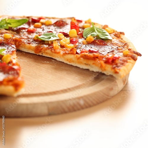 Photo: Pizza with salami, corn and herbs on wooden tray. Pizza with salami, corn and herbs on wooden tray.