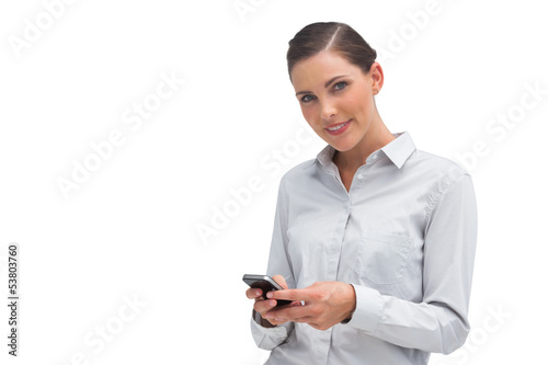 Photo: Smiling businesswoman sending text message Smiling businesswoman sending text message