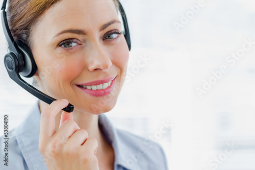 Photo: Call centre operator wearing headset smiling at camera Call centre operator wearing headset smiling at camera