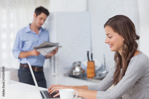 Photo: Attractive woman using her laptop in the kitchen Attractive woman using her laptop in the kitchen