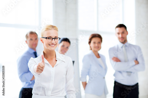 Photo: businesswoman in office showign thumbs up businesswoman in office showign thumbs up