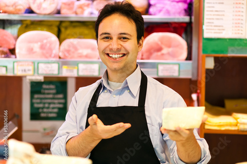 Photo: Smiling shopkeeper showing a product Smiling shopkeeper showing a product