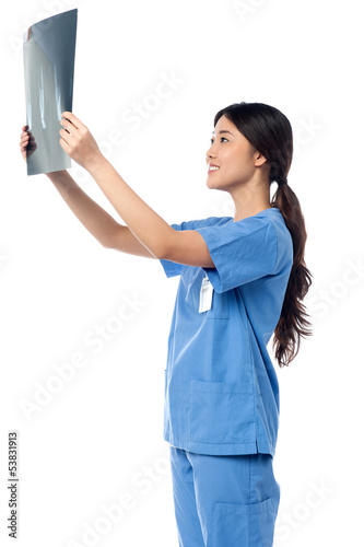 Photo: Female doctor looking at scanned x-ray report Female doctor looking at scanned x-ray report