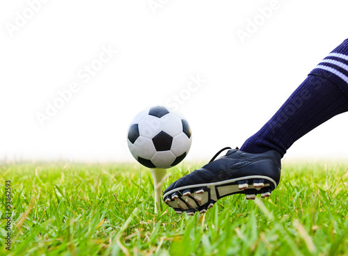 Photo: foot kicking soccer ball on golf tee isolated foot kicking soccer ball on golf tee isolated