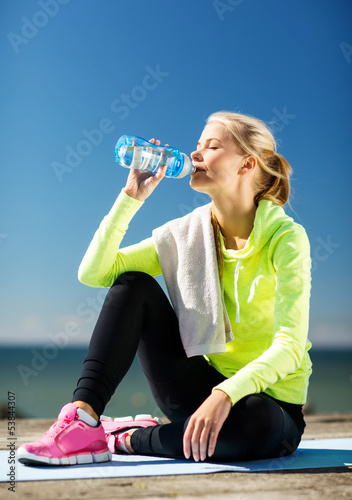 Photo: woman drinking water after doing sports outdoors woman drinking water after doing sports outdoors