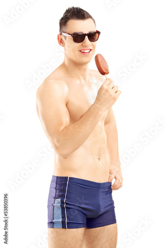 Photo: Young man in swimwear holding a chocolate ice cream Young man in swimwear holding a chocolate ice cream