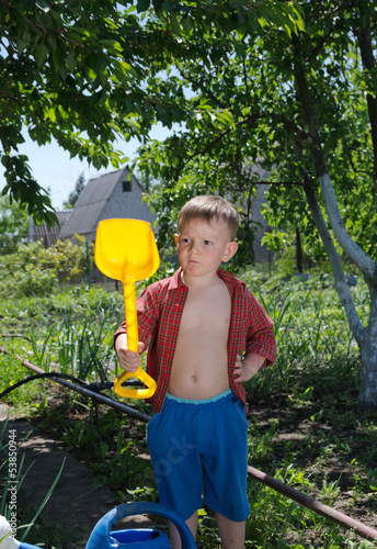 Photo: Young boy with his spade in the garden Young boy with his spade in the garden