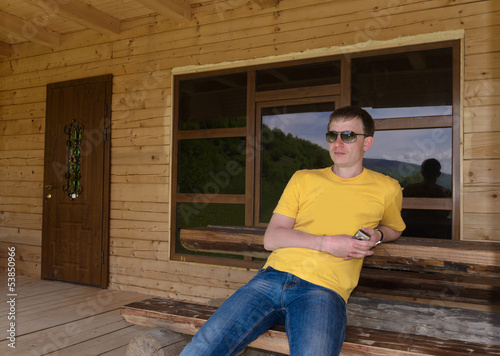 Photo: Man sitting in front of a wooden cabin Man sitting in front of a wooden cabin