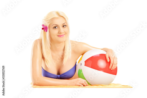 Photo: Beautiful blond female lying on a beach towel and holding a ball Beautiful blond female lying on a beach towel and holding a ball
