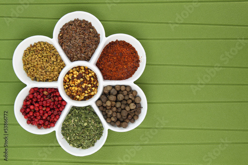 Photo: White porcelain bowl with spices on green background White porcelain bowl with spices on green background