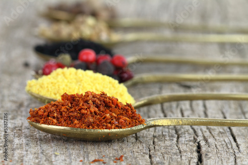 Photo: Old spoons with spices on wooden background Old spoons with spices on wooden background