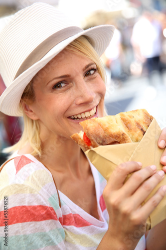 Photo: Cheerful blond girl in Rome eating Focaccia sandwich Cheerful blond girl in Rome eating Focaccia sandwich