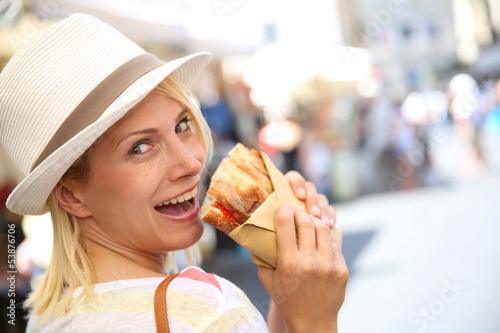 Photo: Cheerful blond girl in Rome eating Focaccia sandwich Cheerful blond girl in Rome eating Focaccia sandwich