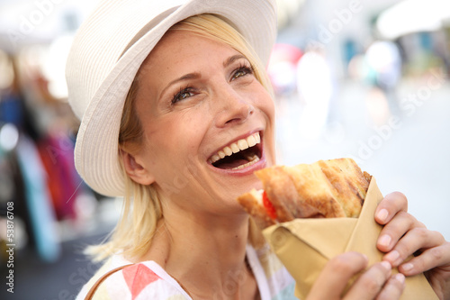 Photo: Cheerful blond girl in Rome eating Focaccia sandwich Cheerful blond girl in Rome eating Focaccia sandwich