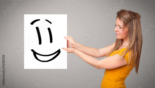 Photo: Young woman holding smiley face drawing Young woman holding smiley face drawing