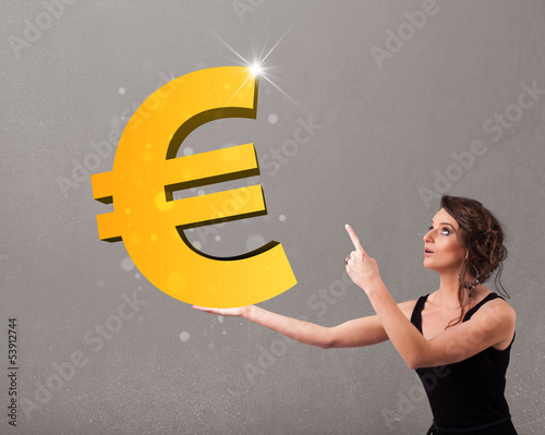 Photo: Beautiful girl holding a big 3d gold euro sign Beautiful girl holding a big 3d gold euro sign
