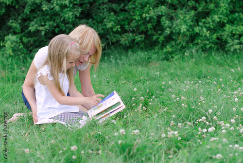 Photo: Mother and daughter reading book in the park Mother and daughter reading book in the park