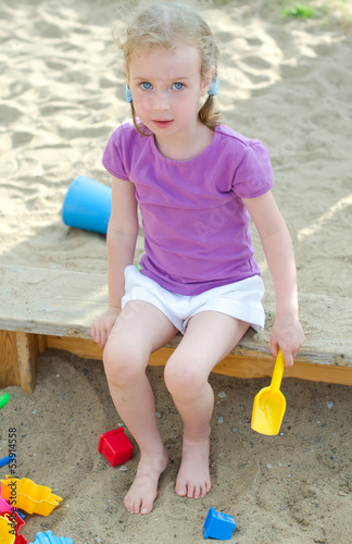 Photo: Little girl sitting near sandbox Little girl sitting near sandbox